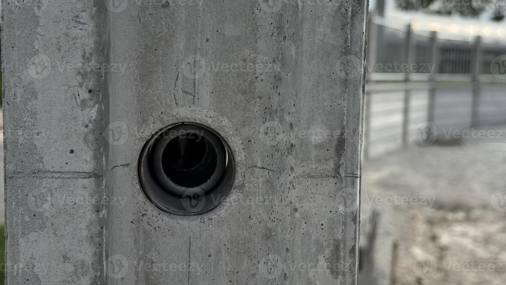 Concrete Wall with Circular Opening An industrial image shows a close-up of a gray concrete wall, a circular opening in its surface, highlighting texture, detail, and construction elements. photo
