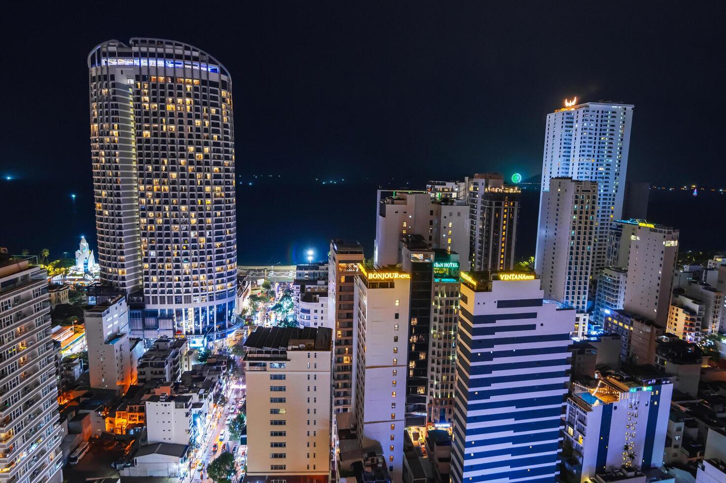 Aerial top view above drone of city Nha Trang center with skyscrapers and sea at night. Nha Trang, Vietnam - July 17, 2024 photo