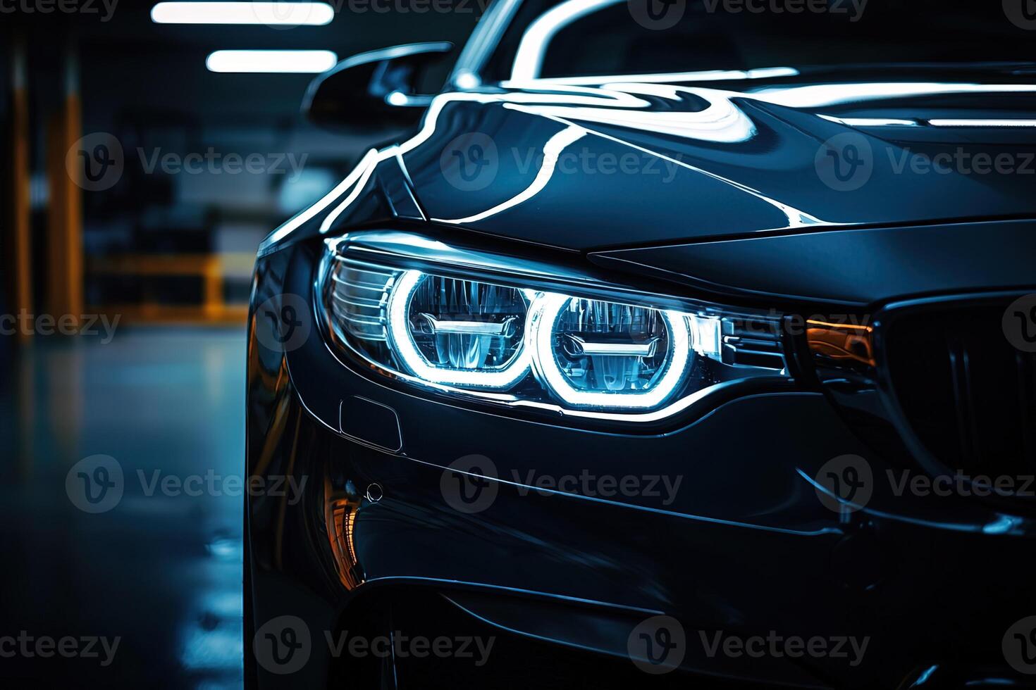 Close-up view of a black car with headlight shining in a dark parking lot at night. Blurred city background creates a dramatic and moody atmosphere. photo