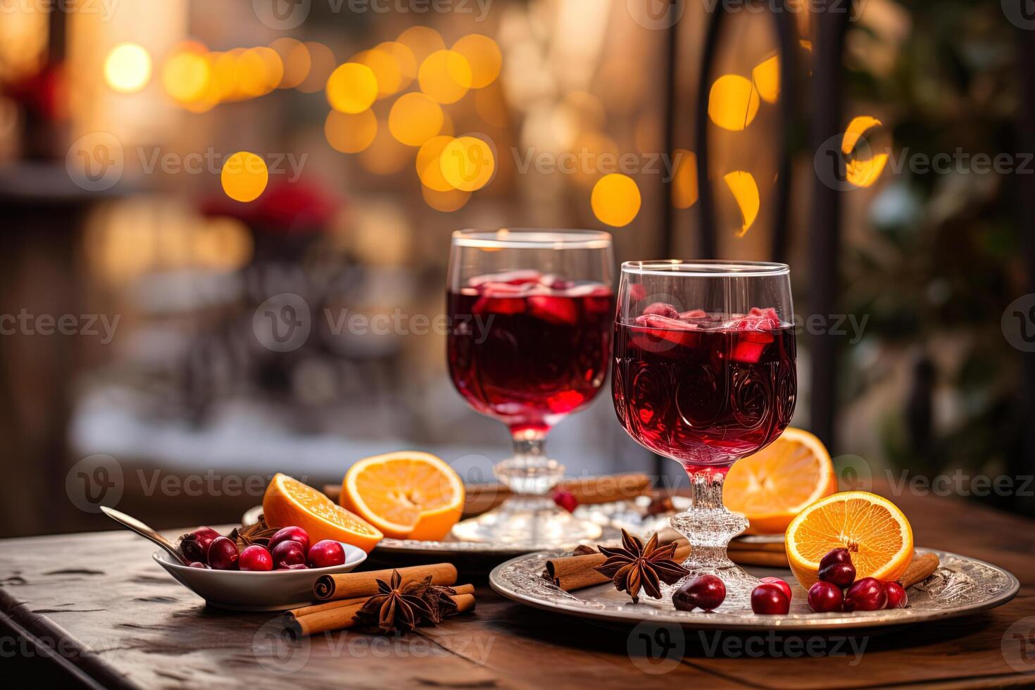 close-up two glasses of mulled wine and various spices cinnamon, anise stars and berries stand on wooden table of street cafe with blurred bokeh evening background photo