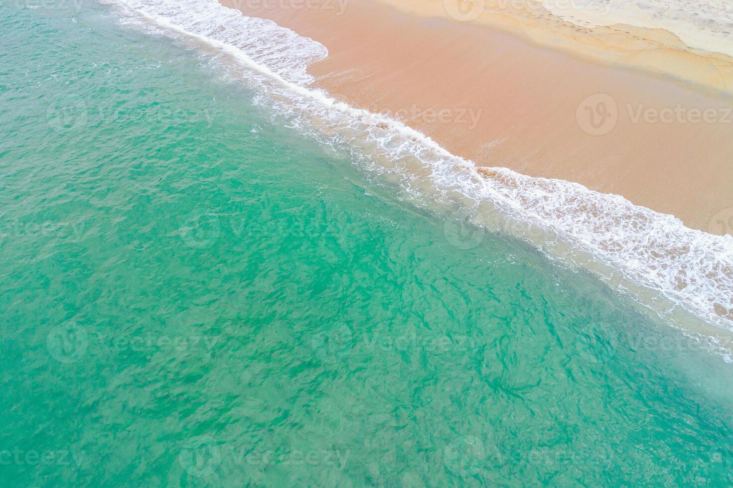 drone shot of waves and foam on a clear beach abstract pattern of waves, foam, and sand from above photo
