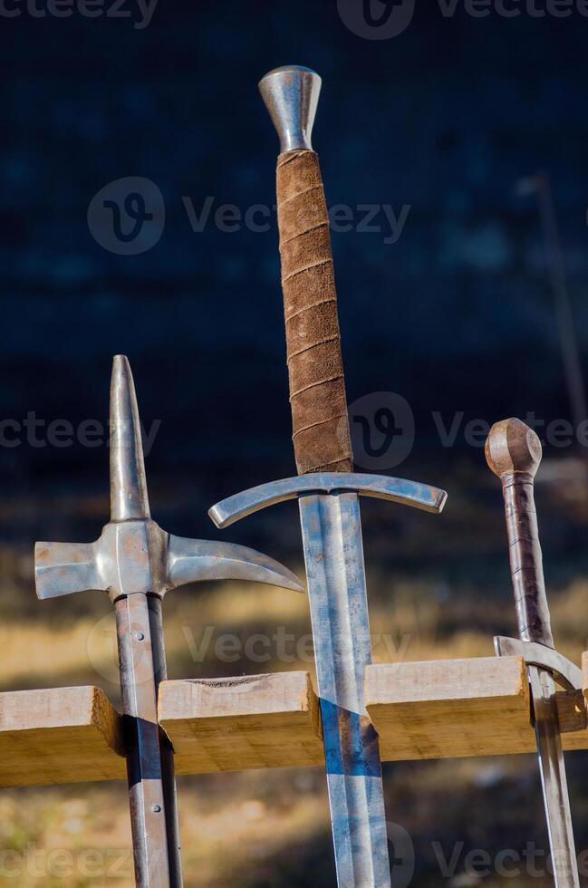 ancient arms displayed vertically in a wooden stand in a reenactment medieval event medieval combat weapons photo