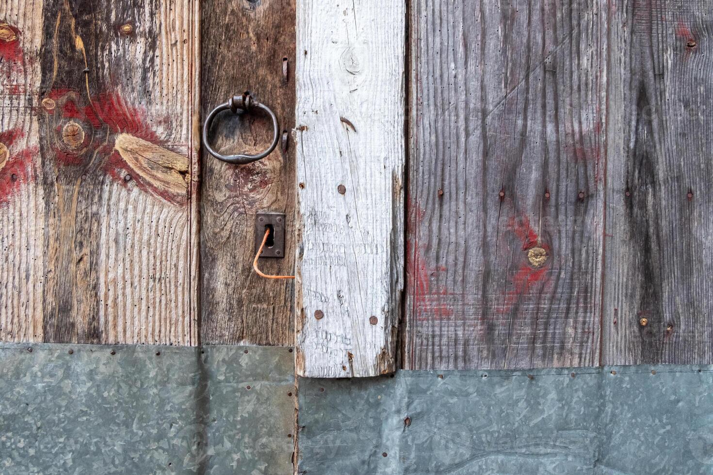 old door made of pieces of wood and sheet metal texture background of a weathered wood fence photo