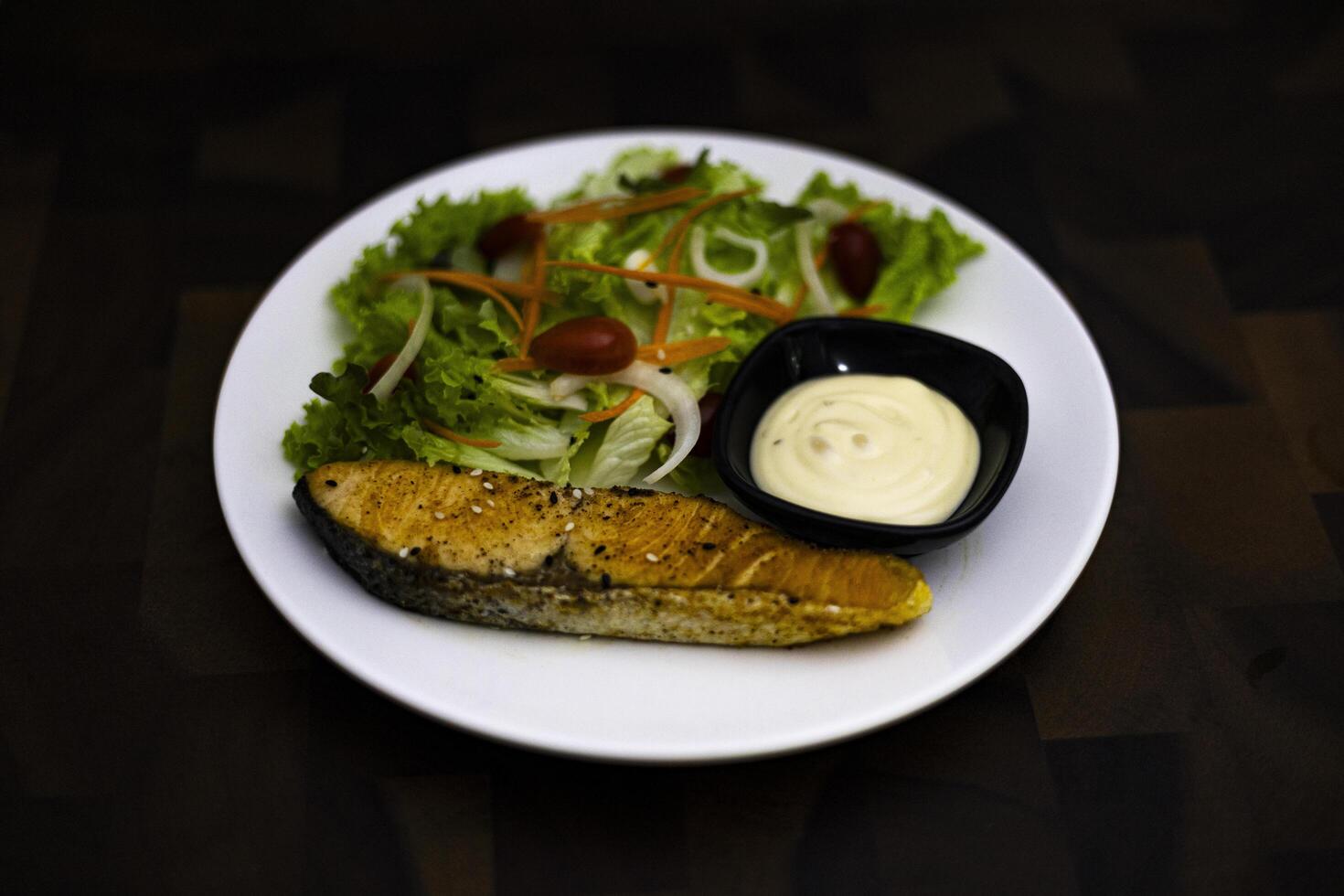 Grilled Salmon Salad On A White Plate Placed On A Wooden Table photo