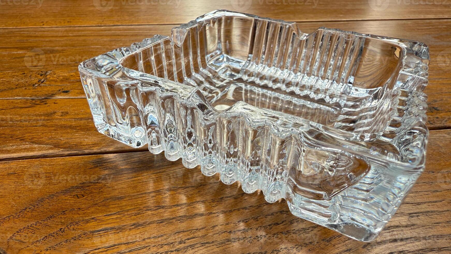 Elegant crystal ashtray on rustic wooden table, symbolizing relaxation and style, suitable for vintage decor or retro themes photo
