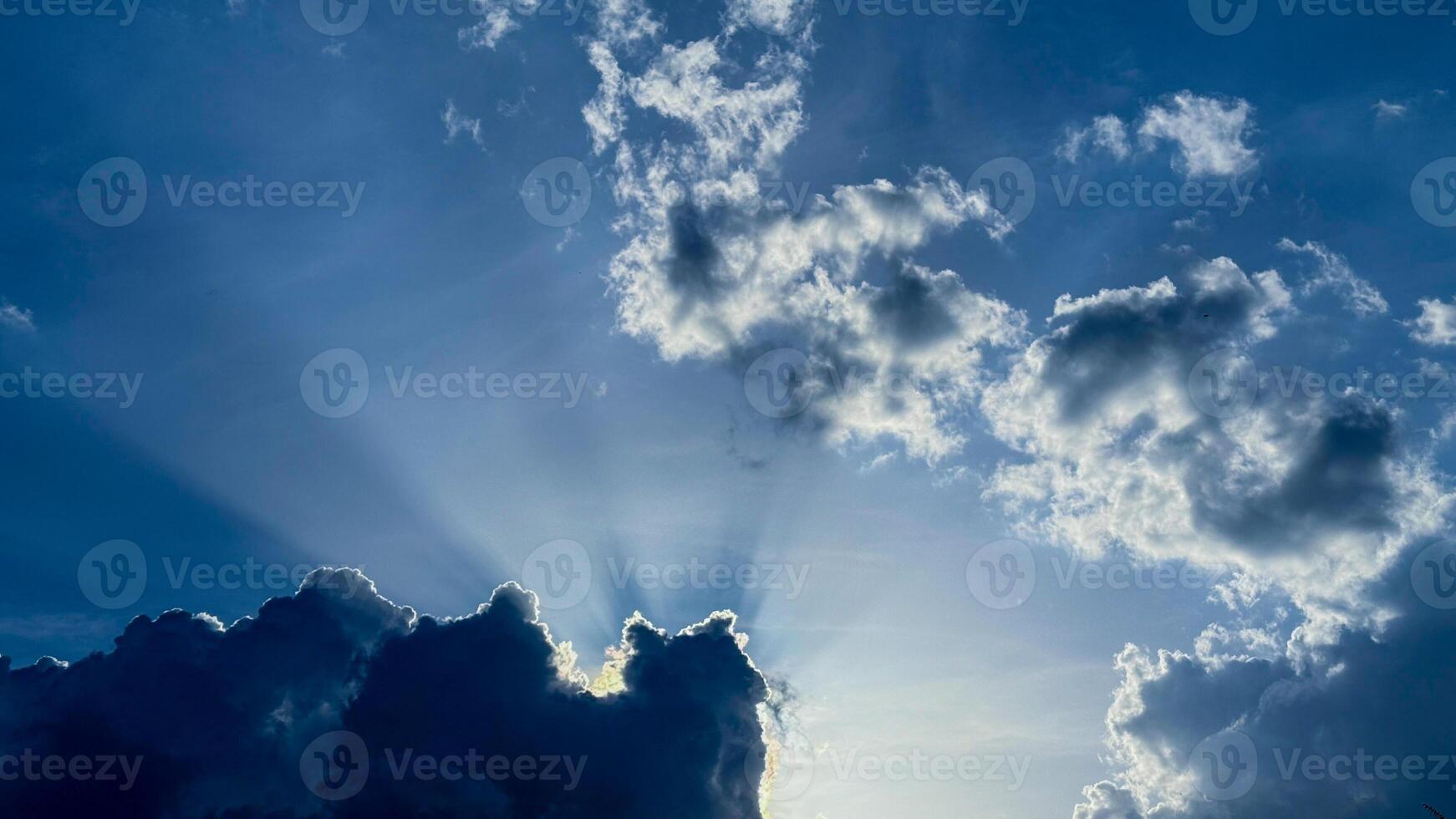 Majestic sunbeams pierce cotton cloud canopies, evoking celestial wonder and Solstice celebrations, capturing ethereal lights gentle embrace photo