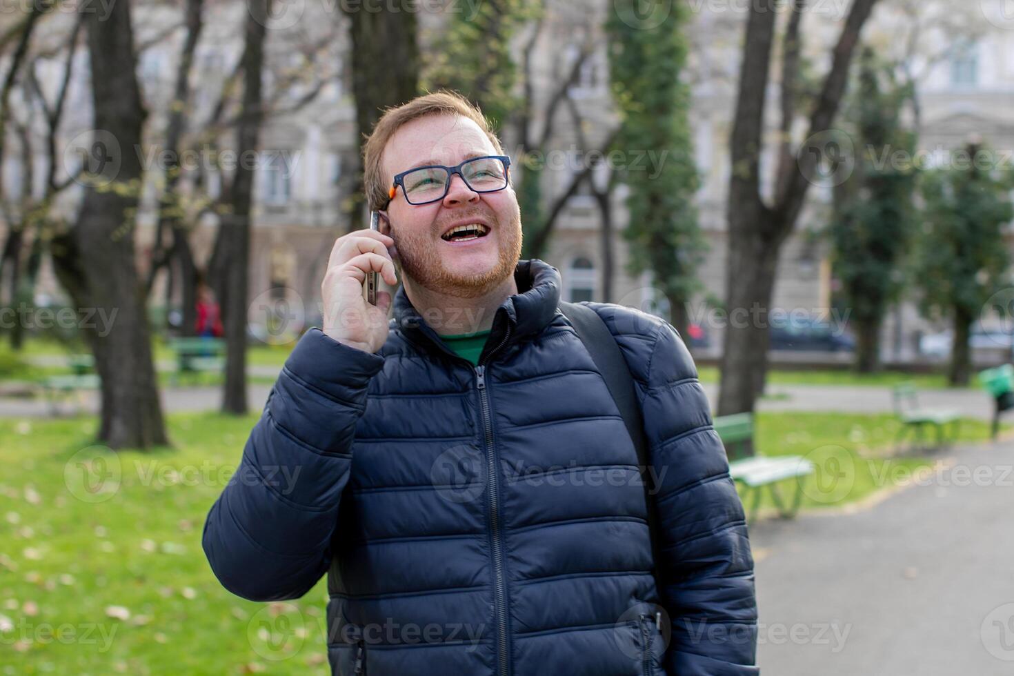 A jovial redheaded Caucasian man chatting under springs gentle embrace, mirthful connection, World Laughter Day, digital detox moments photo