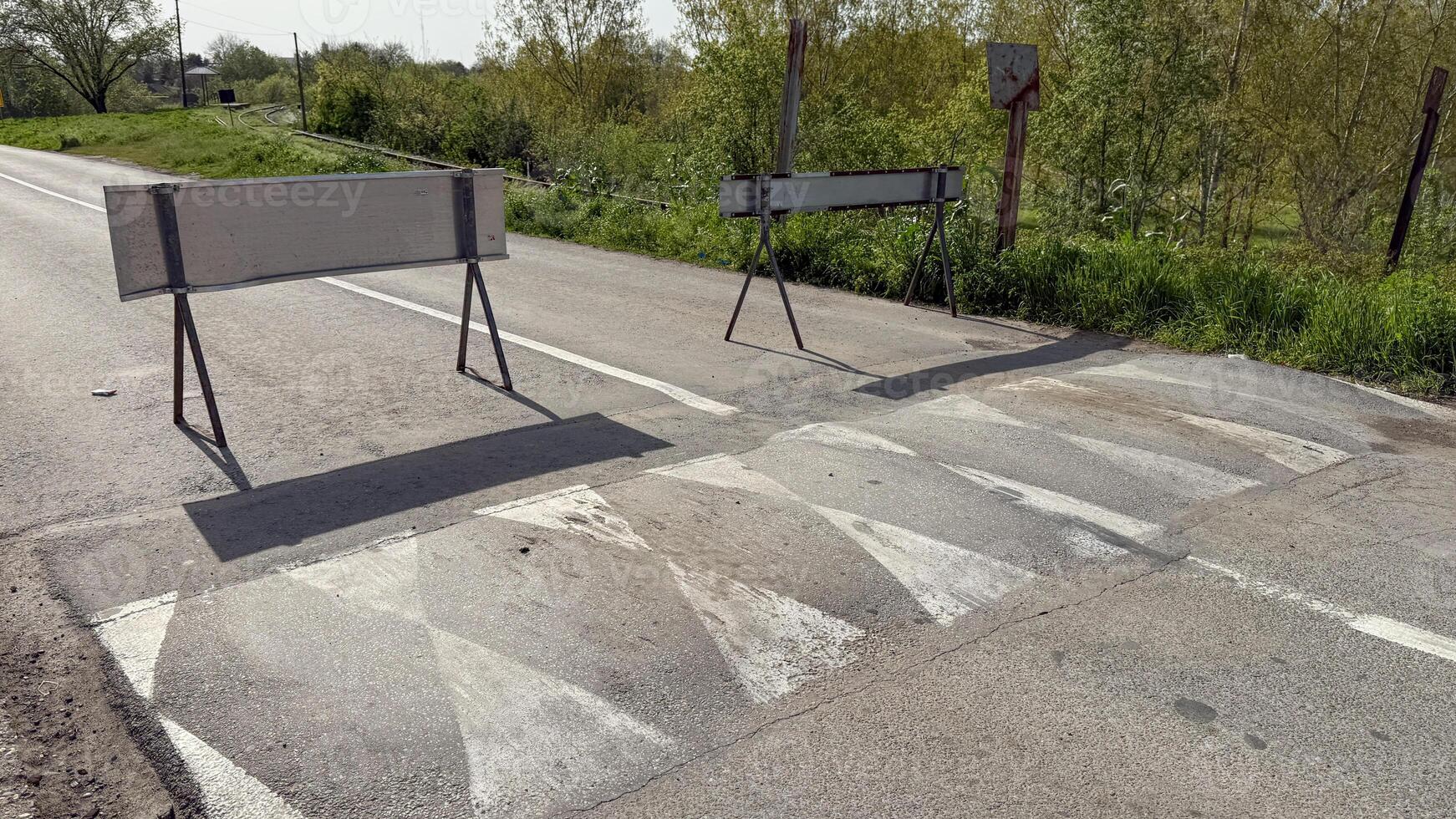 Empty rural road with traffic barriers under sunny sky, emphasizing travel safety and rural infrastructure, Earth Day concepts photo