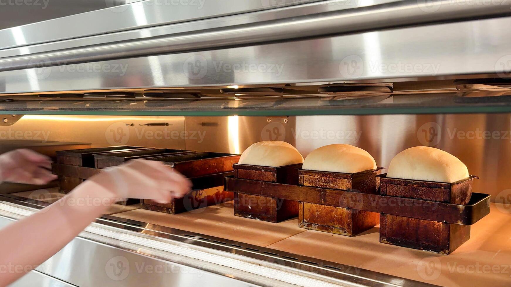 Bakers hands placing fresh dough in oven for delicious homemade bread, celebrating artisan bakery and cozy holiday baking photo