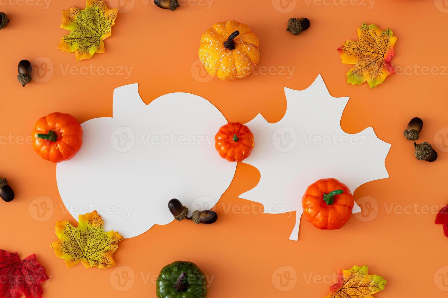 Creative autumn pattern of colorful autumn leaves, pumpkins and nuts with leaf and pumpkin shape paper card note copy space on orange background. Minimal season concept. Fall aesthetic. Flat lay. photo