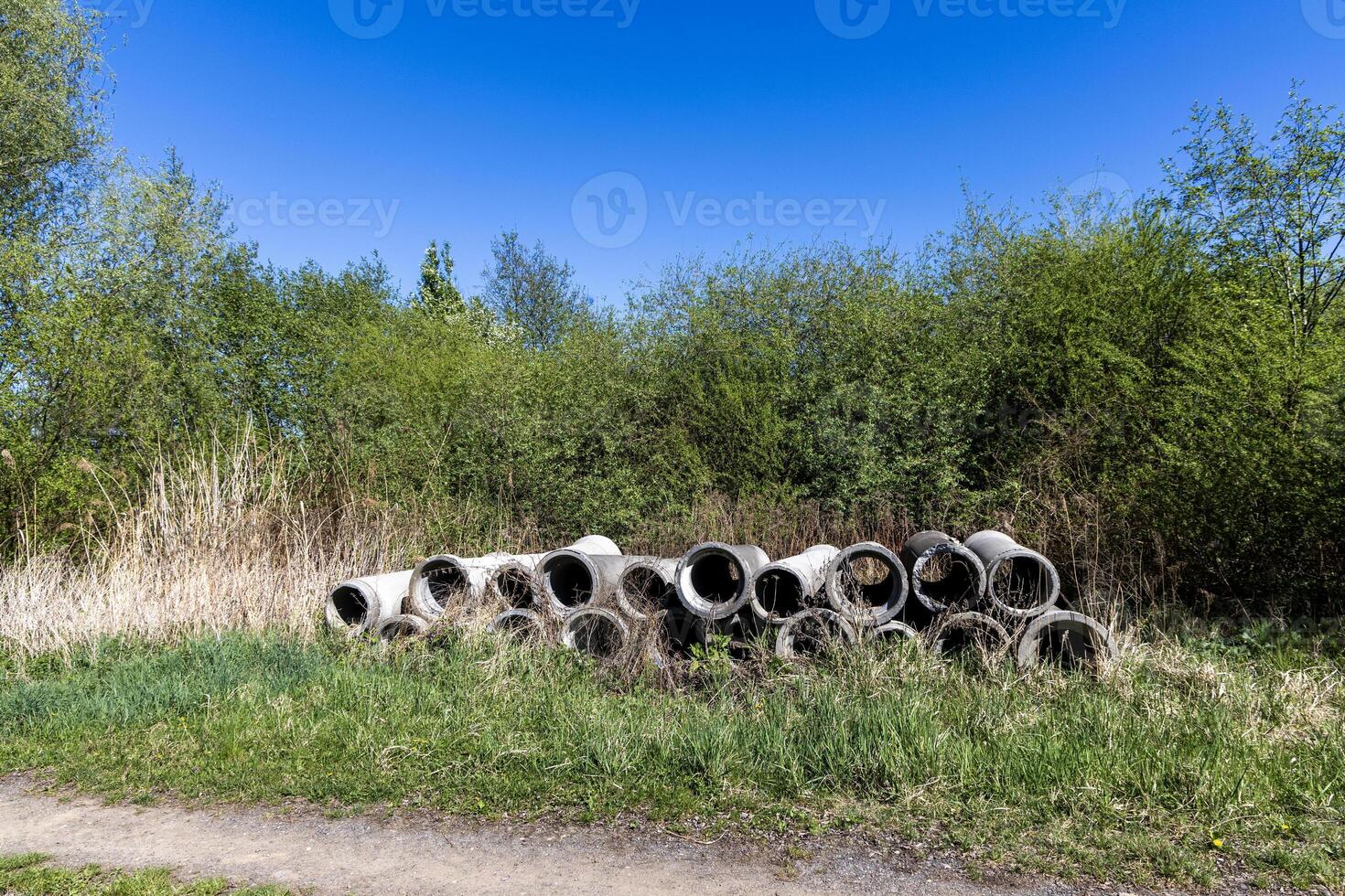 Old concrete pipes dumped by a country road. Poland photo