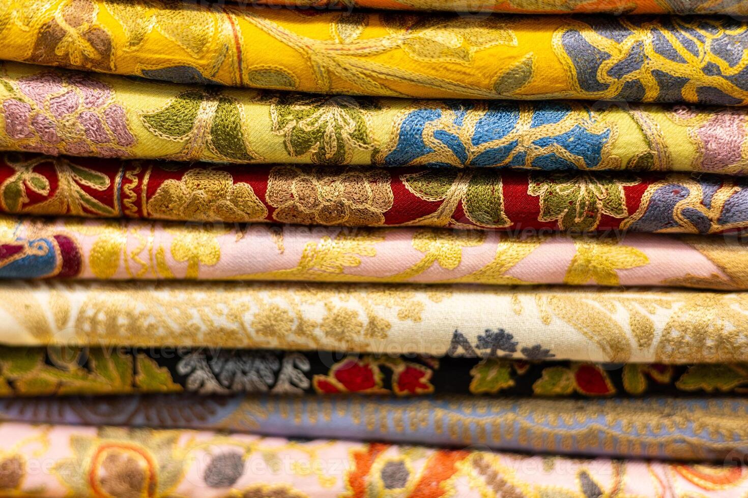 Colorful embroidered fabrics stacked neatly in a textile shop showcasing intricate designs photo