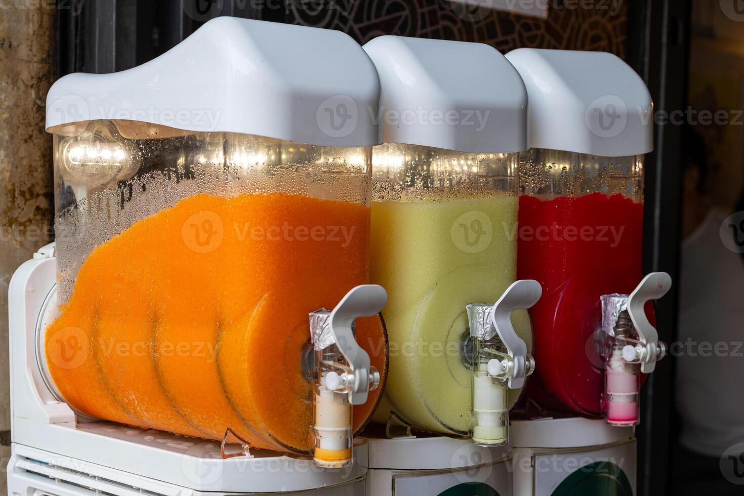Colorful beverage dispensers filled with tropical flavors in a vibrant market setting during the afternoon photo