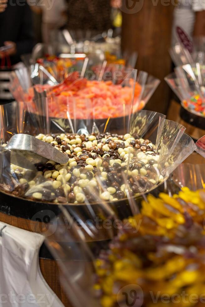 Colorful array of candies displayed in large containers at a festive market during the evening hours photo