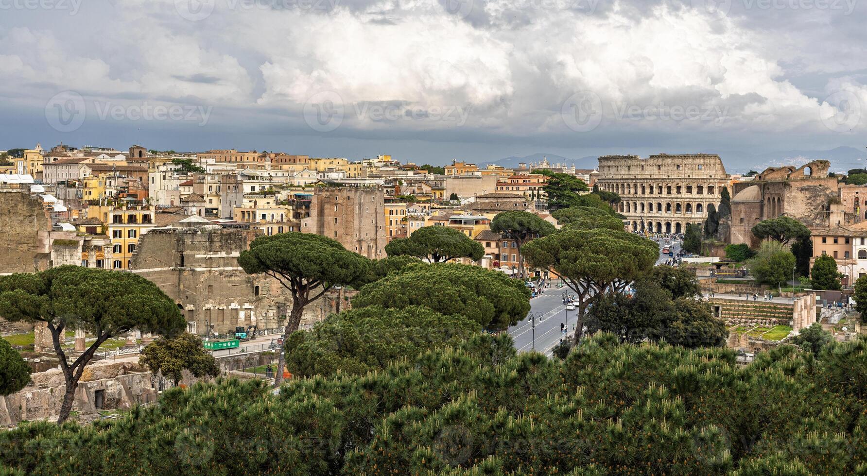 Historic landscape featuring ancient ruins and the Colosseum in Rome with overcast skies during midday photo