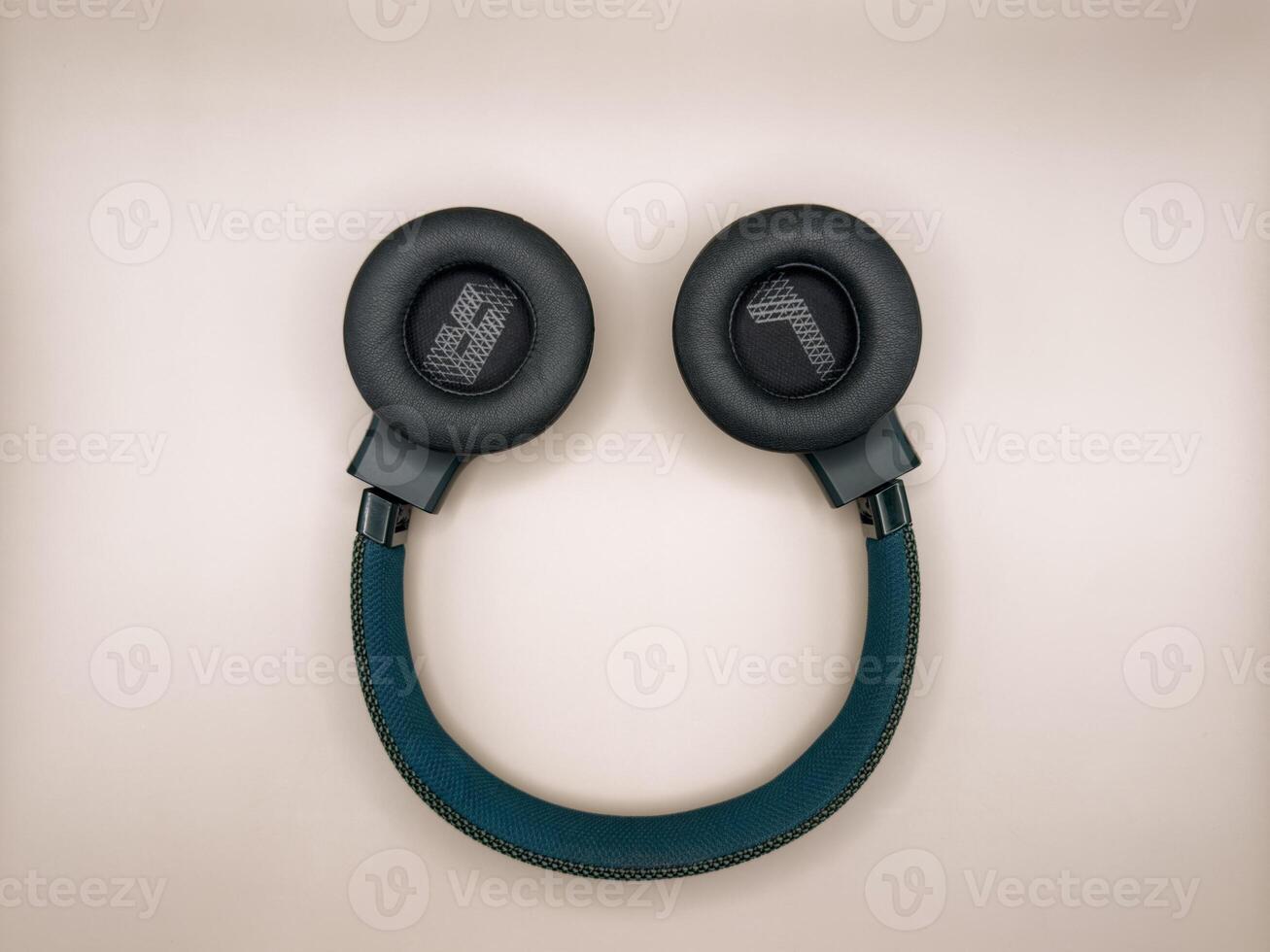 Headphones are full-size, large, green, with soft earphones turned outward, in which the left and right earphones are indicated, and a soft bow lies in the center of the image, inverted on a pink photo