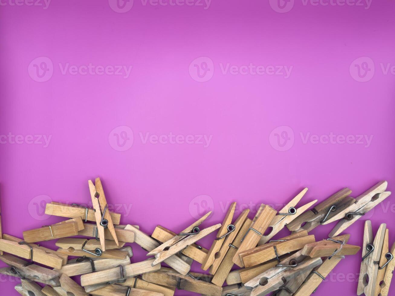 Old wooden clothespins centered at the bottom of the image on a purple background top view photo