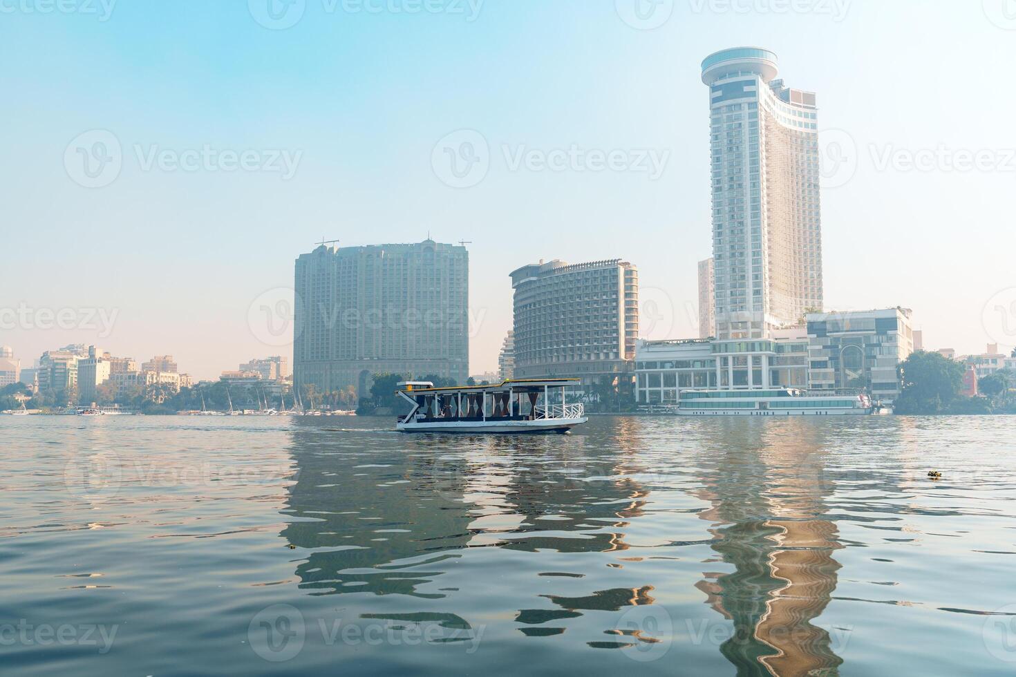 Cityscape view of a river with a boat passing by and modern buildings in the background during the early morning photo