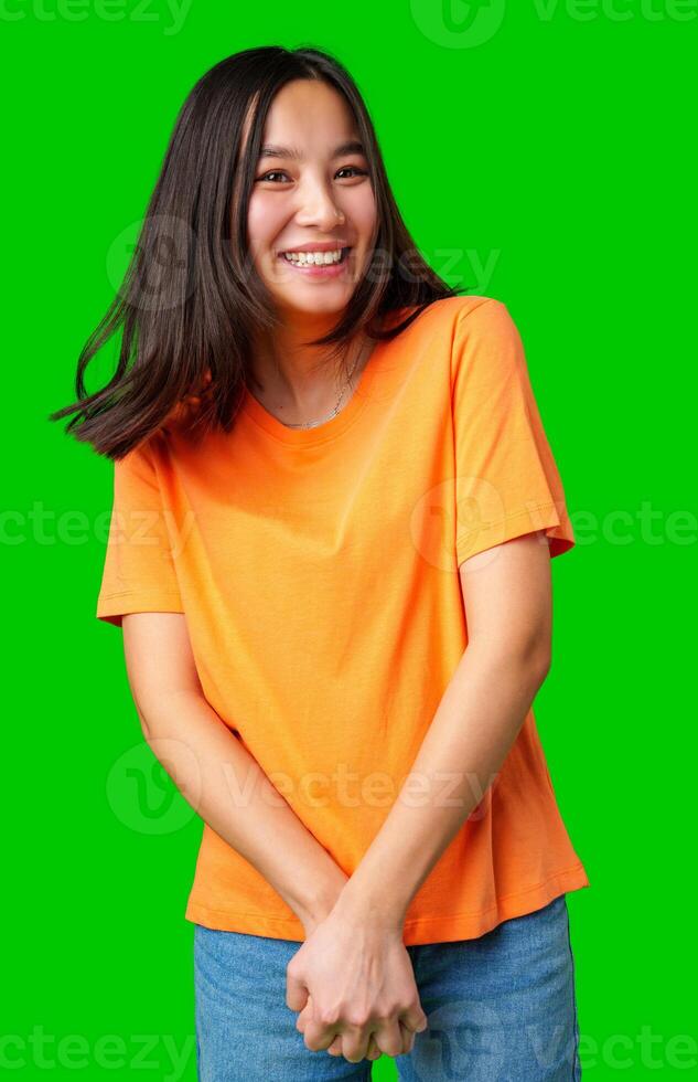 Smiling young woman enjoying herself in a vibrant orange shirt against a bright green background photo