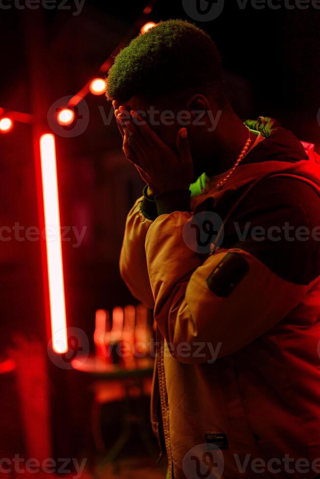 Emotional moment captured at night in a vibrant urban setting with red lights and a contemplative figure photo