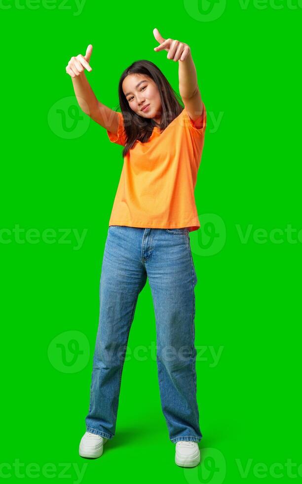 Young person in bright orange shirt poses playfully on green background showcasing energy and confidence photo