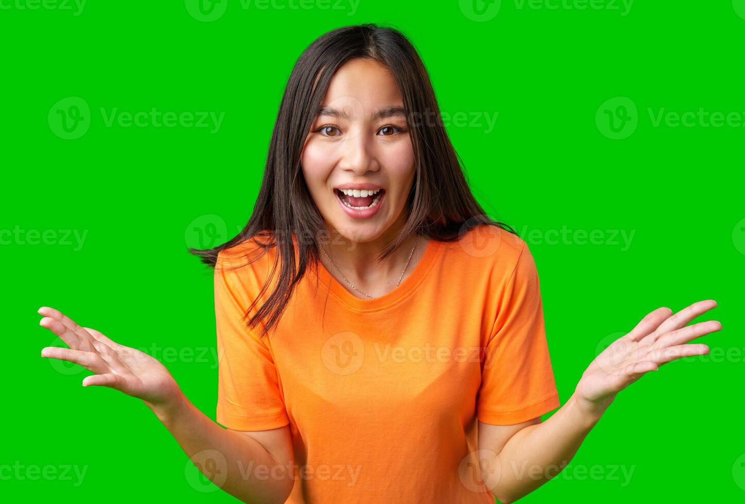 Happy woman wearing orange shirt expressing excitement with hands raised against a bright green background photo