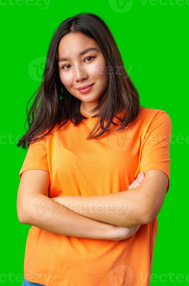 Young woman with long hair in bright orange shirt poses confidently against green background photo