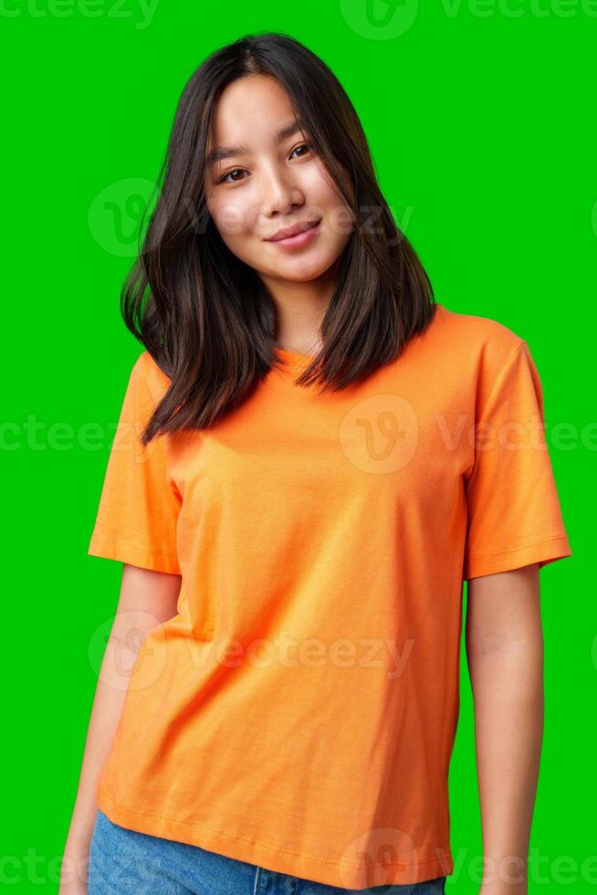 Young woman poses confidently in an orange t-shirt against a vibrant green background photo