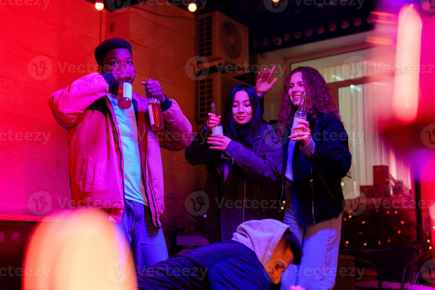 Friends enjoying drinks and dancing at a lively party in a cozy indoor venue during the evening hours photo
