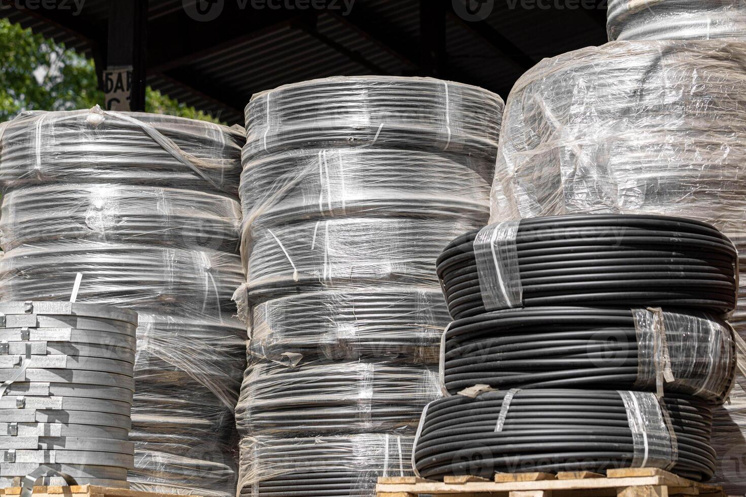 Stacks of cables wrapped in polyethylene in an open storage area in bright daylight. photo