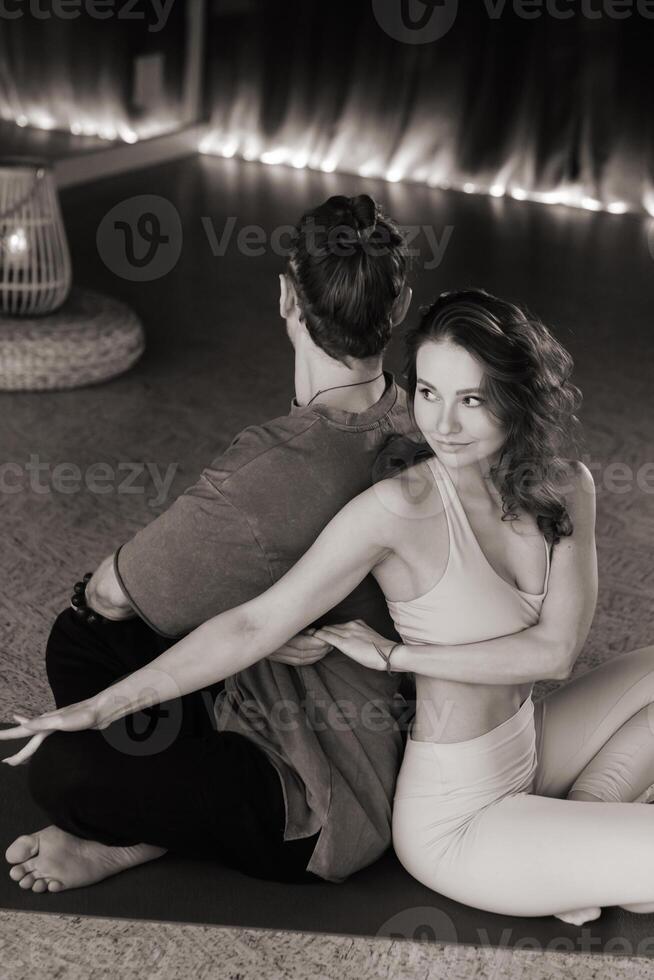 Couple practicing partner yoga in a serene indoor studio during an evening session with warm lighting and calming atmosphere photo