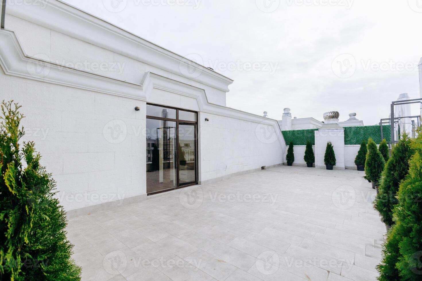 A large, elegant white building has a spacious patio and trees photo