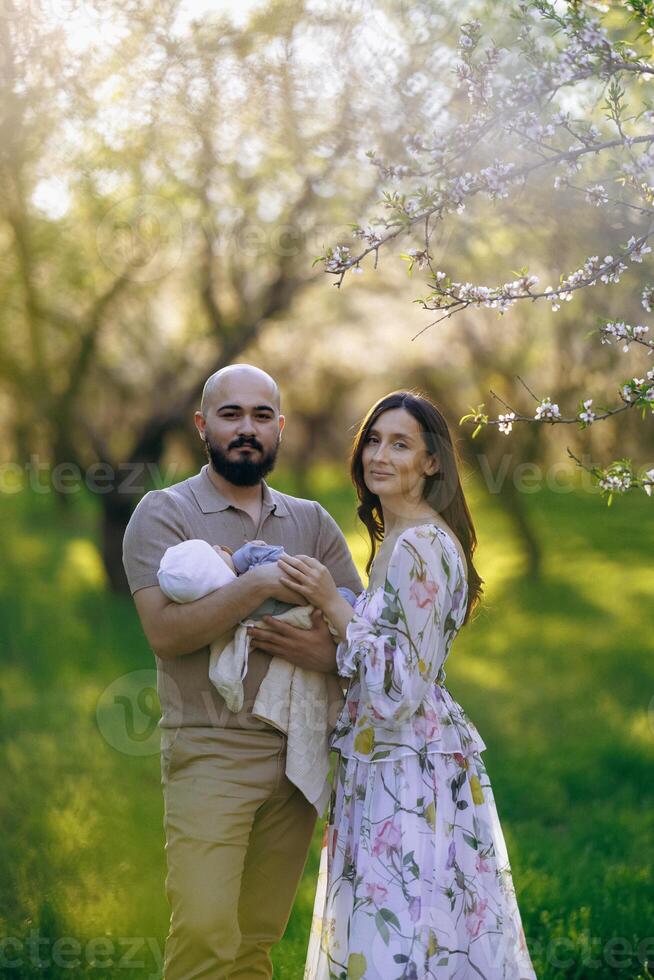 A man and a woman are joyfully holding a baby in a lovely park photo