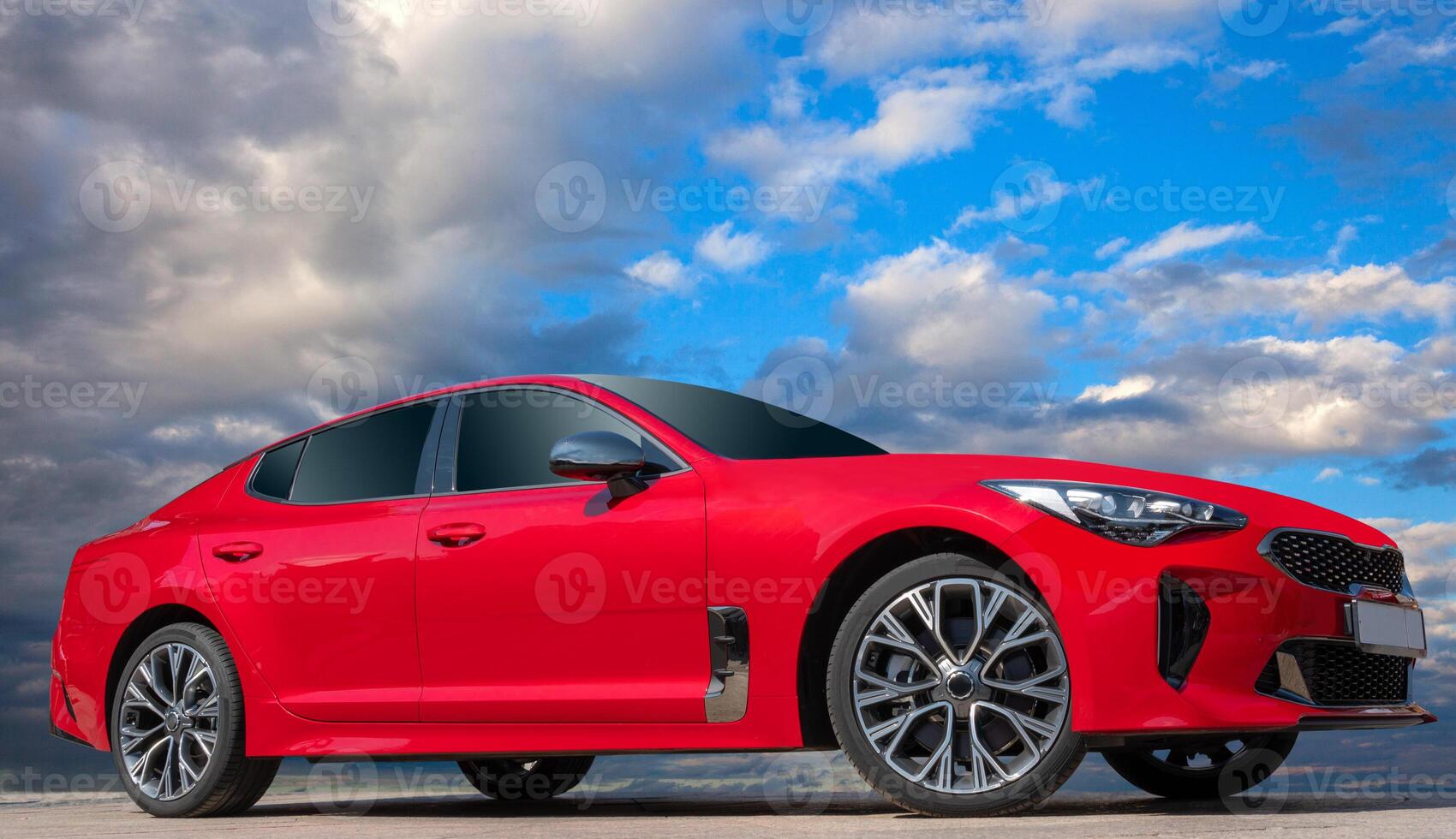 Red car on a blue sky background with white clouds. A stylish, modern, bright image of an avto mobile. photo