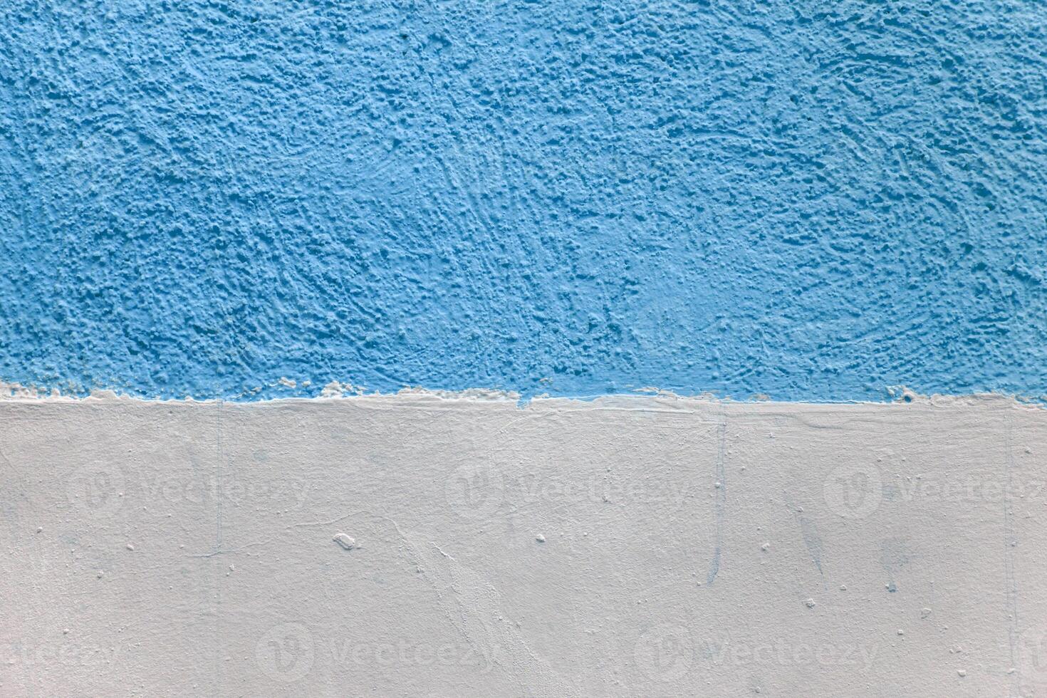 A wall with a blue and white stripe. The blue stripe is painted on top of the white. photo