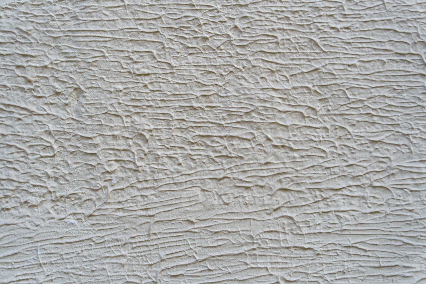 A wall with a white paint that has a texture. The texture is made up of lines and swirls. photo
