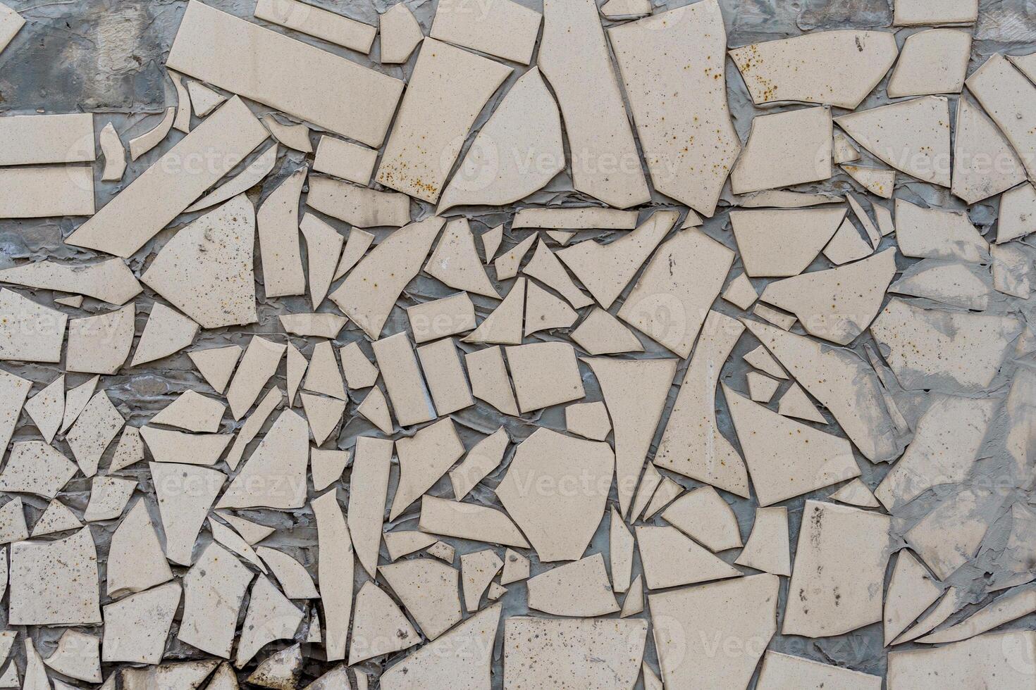 A wall with many pieces of broken tiles. The wall is white. The tiles are broken in different shapes and sizes. photo