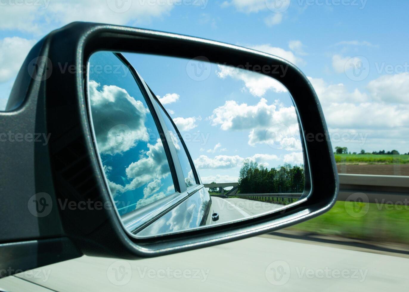 Road and clouds reflected in car side mirror photo