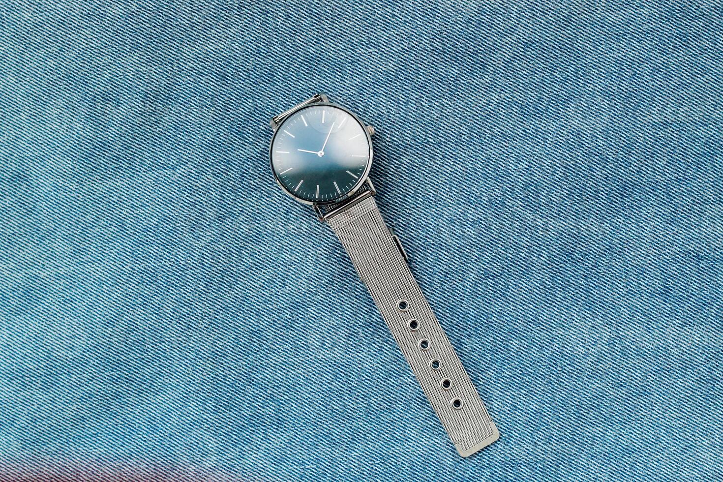 Elegant stainless steel watch resting on denim fabric in casual setting photo
