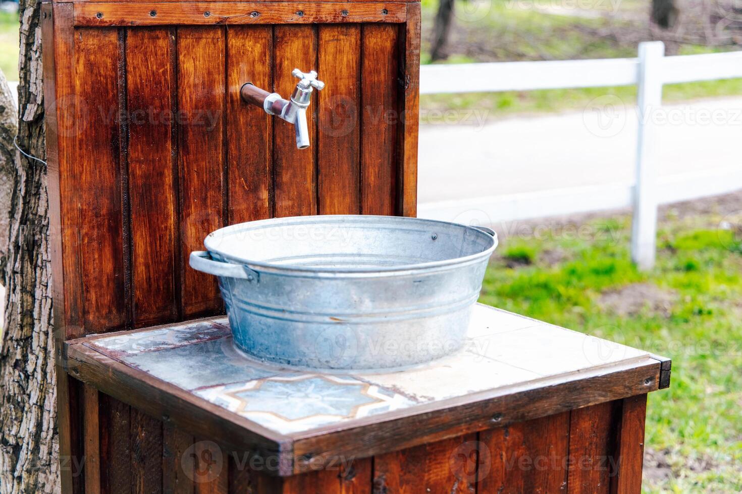 Rustic outdoor water station with metal basin and wooden structure in a natural setting photo