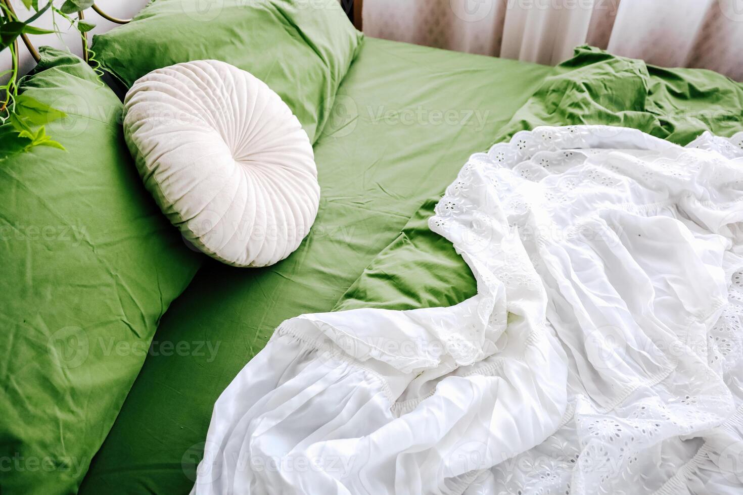 Cozy green bedding arrangement with white blanket and decorative pillow in a bright room photo
