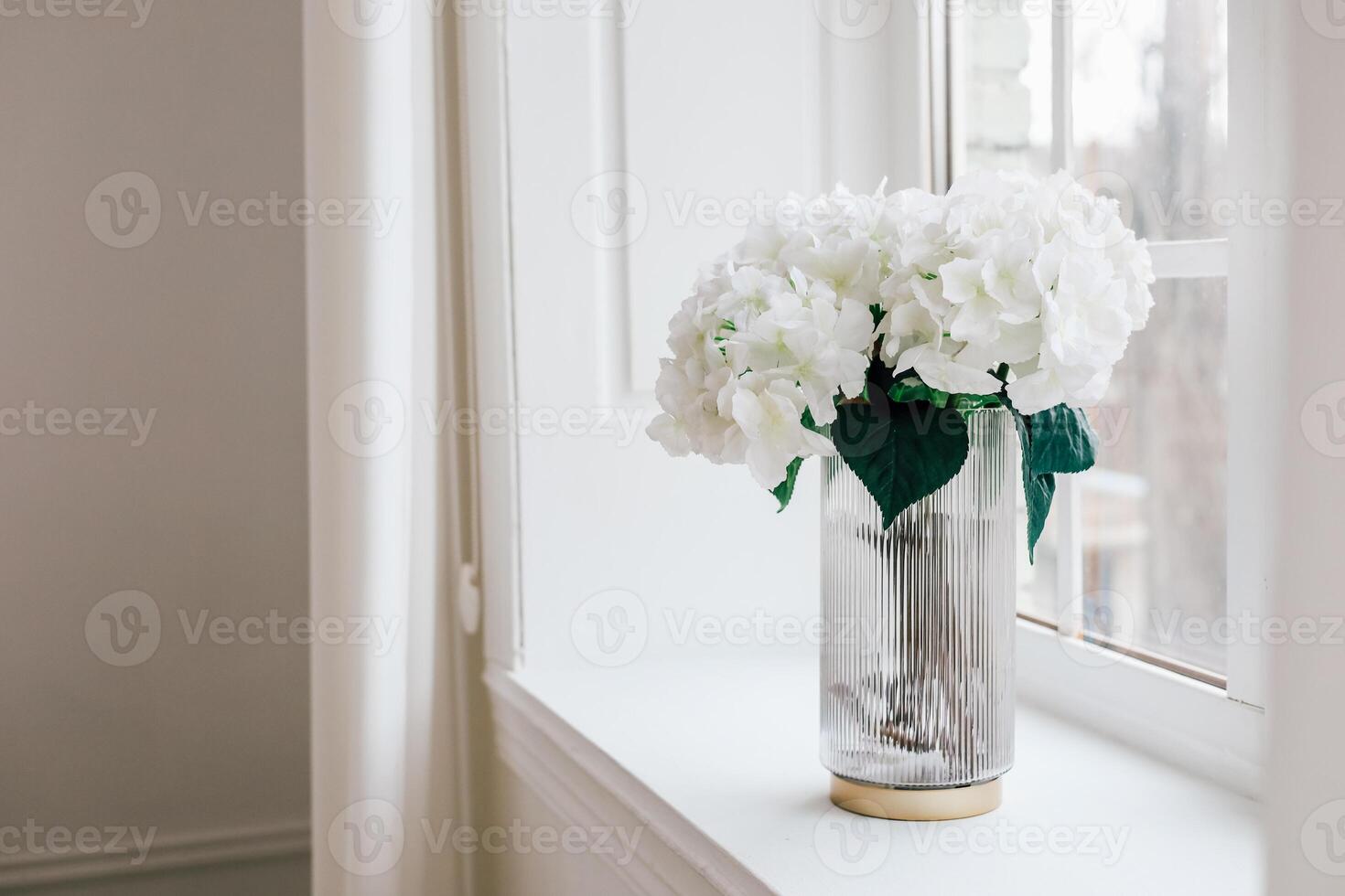 Elegant white flowers in a glass vase brighten a sunlit windowsill in a modern interior space photo