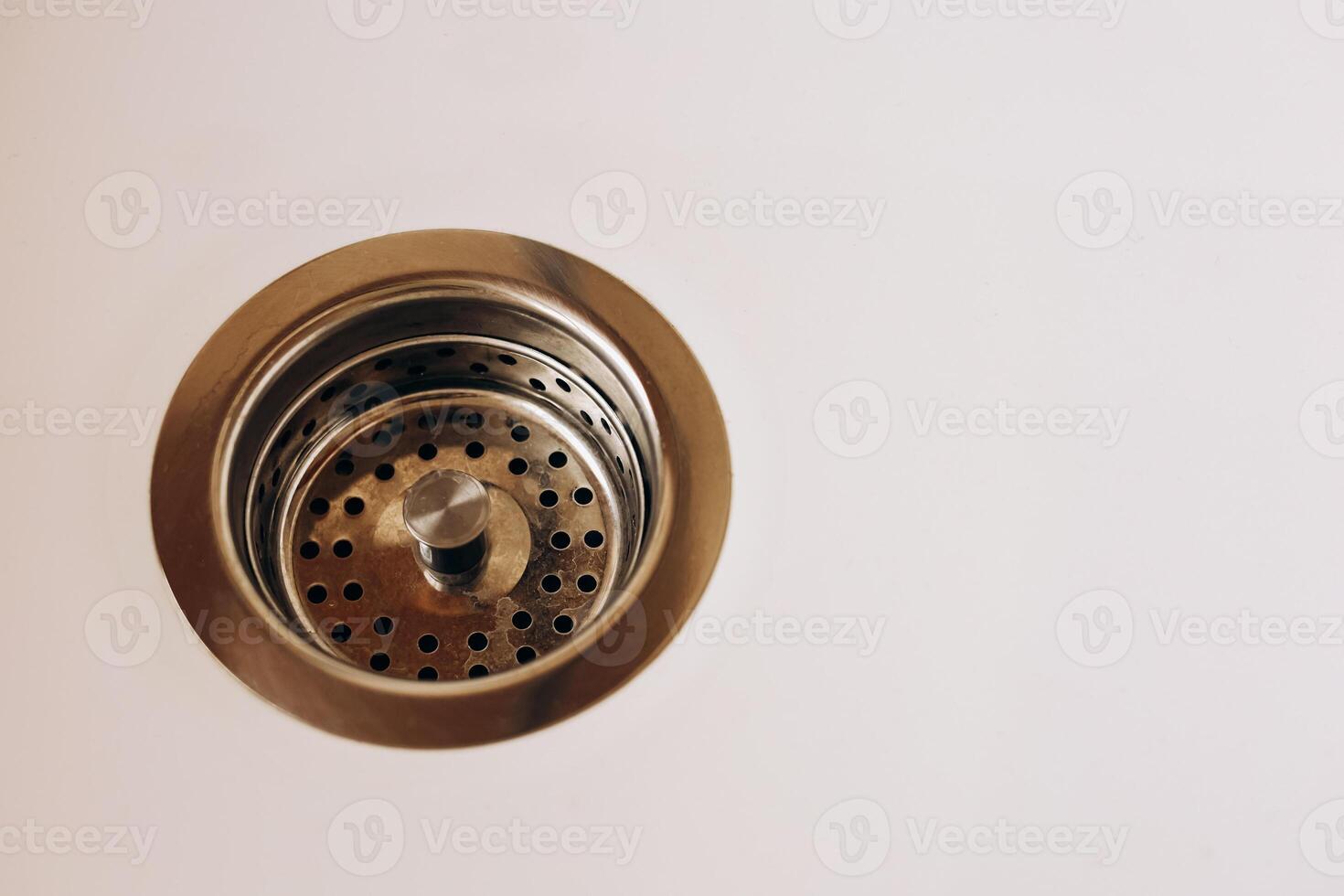 Drain with metal strainer on white surface in modern kitchen photo