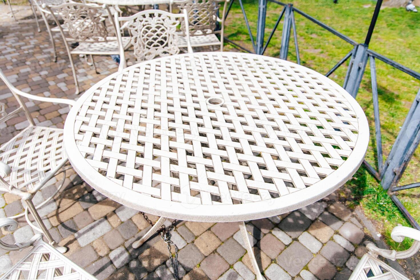 Outdoor metal table and chairs create a cozy gathering spot in a sunlit garden during midday photo