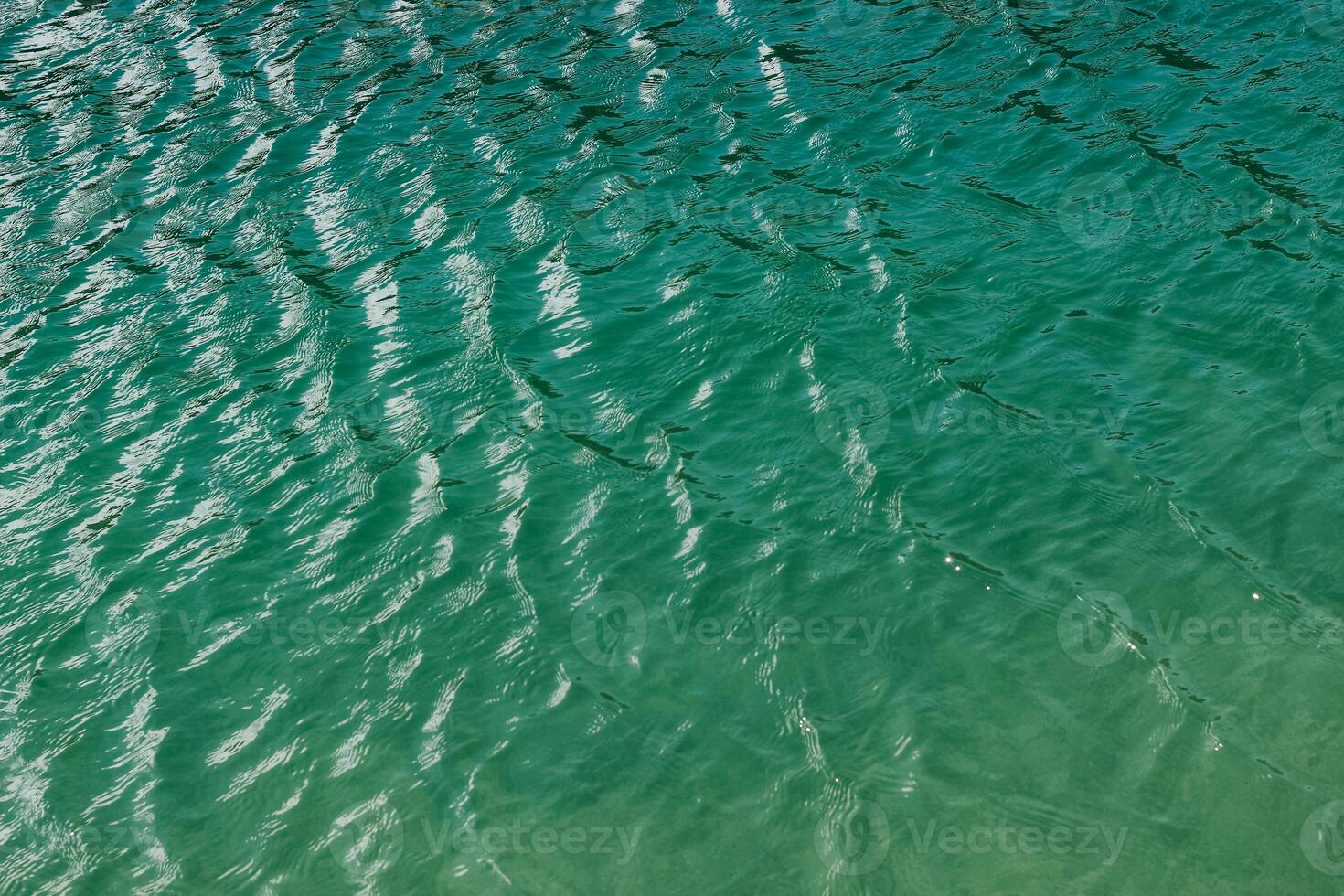 Calm ripples on turquoise waters reflect soft sunlight in a serene coastal landscape photo