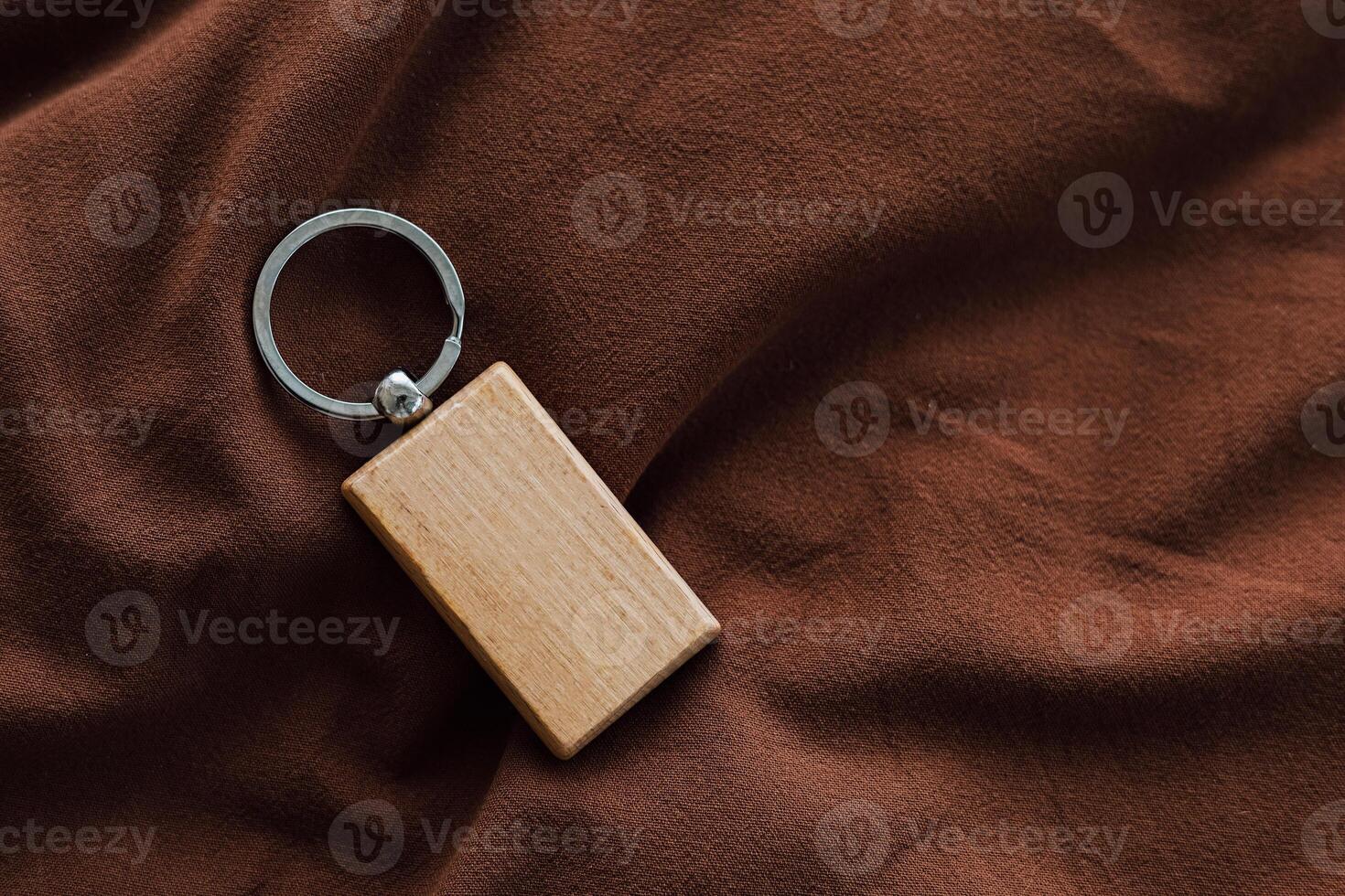 Wooden keychain resting on brown fabric showcases minimalist design and craftsmanship photo