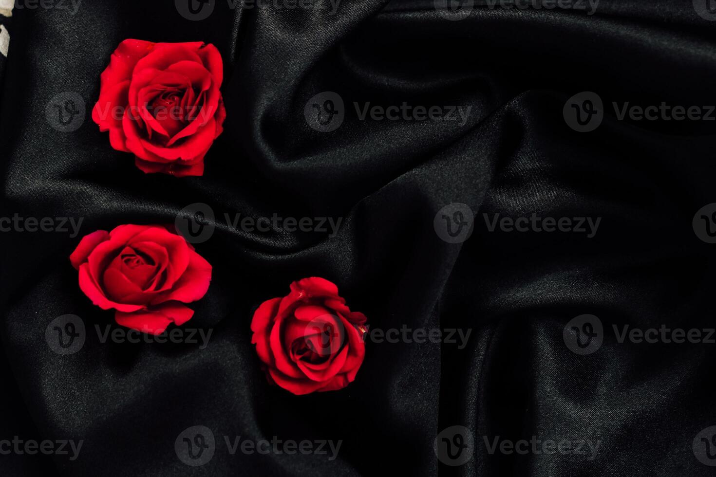 Soft black fabric with vibrant red roses arranged artistically for a romantic atmosphere photo