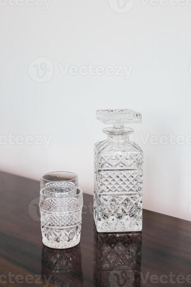 Elegant crystal decanter set on a polished wooden surface with warm lighting photo