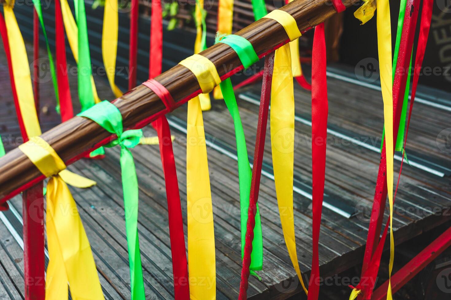 Colorful ribbons adorn wooden railing at cultural celebration in a garden setting photo