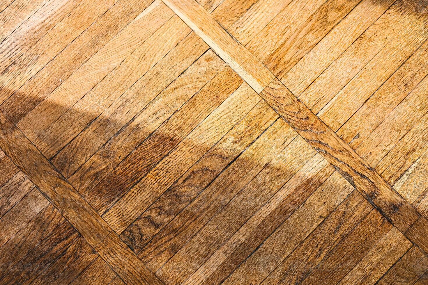 Wooden floor with diagonal patterns and soft sunlit shadows creating a warm ambiance photo